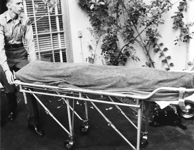 The coroner wheels Monroe's body out of her home where she was found dead in 1962
