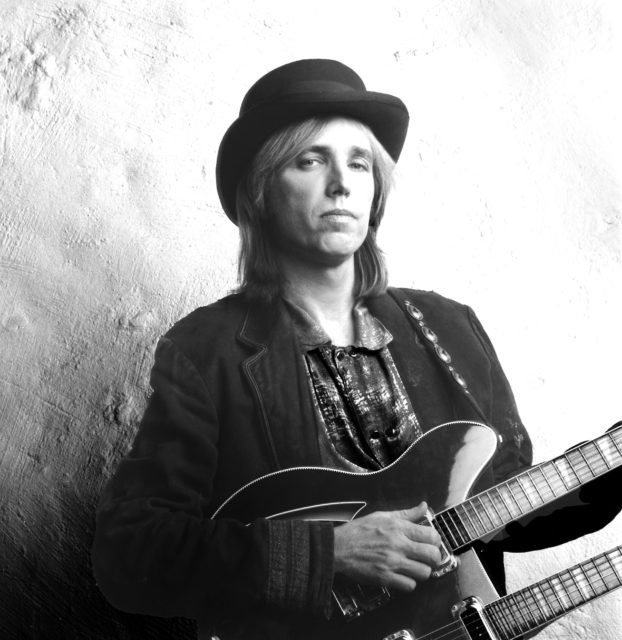 Headshot of Tom Petty wearing a hat and holding a guitar