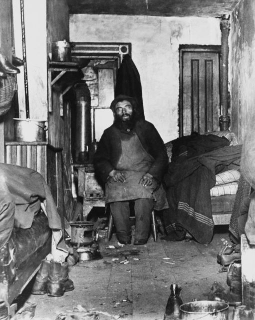 A worker sits in a messy tenement apartment