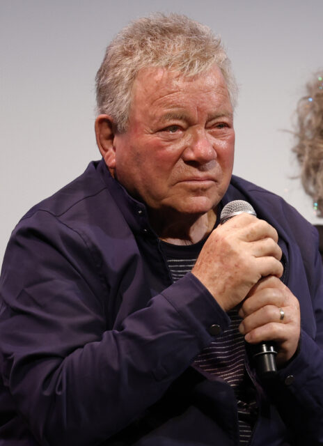 William Shatner holding a microphone with both hands