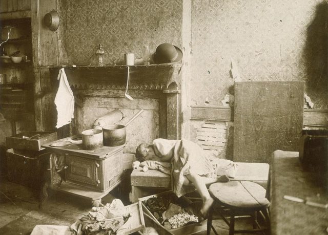 A little girl lays on a bench in a run down tenement 