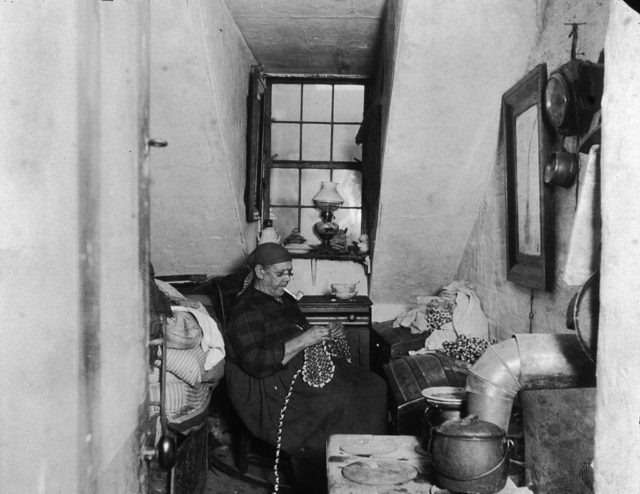 A woman knits while in her tiny New York tenement apartment
