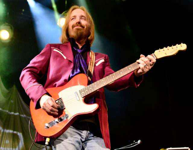 Tom Petty holding a guitar on stage