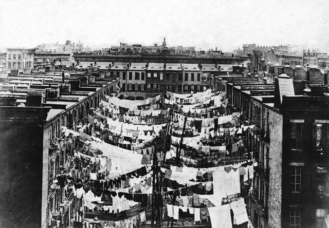 A photo of the tenement slums of New York City shows laundry on clothes lines