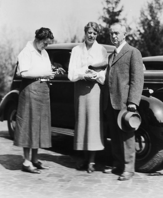 Lorena Hickok and Eleanor Roosevelt in front of a car, a man stands to their left