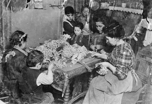 Children help their mother made artificial flowers by hand