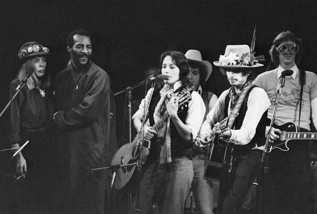 Popular musicians from the 1970s perform at a benefit concert, including Bob Dylan and Joni Mitchell