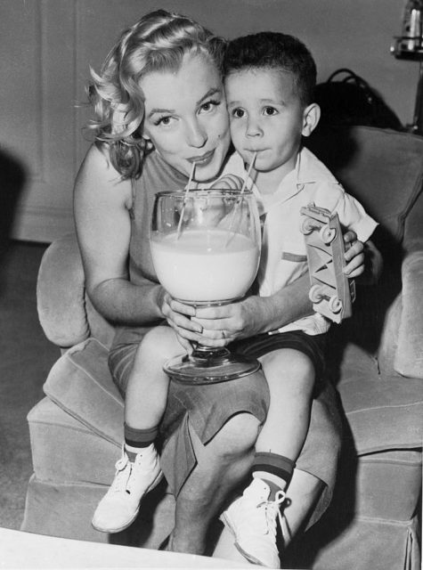 Monroe shares a large glass of milk with a young boy