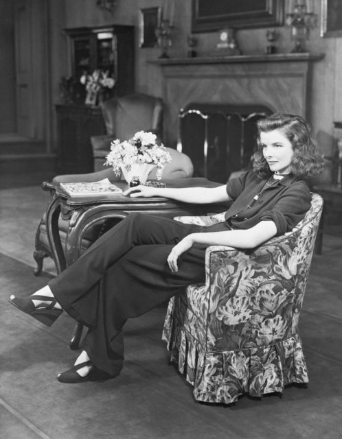 Katharine Hepburn sitting in a chair beside a table