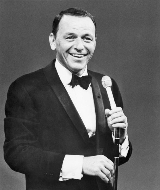 Frank Sinatra in a suit holding a microphone