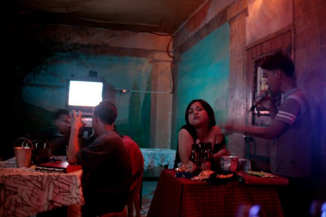 People sitting in a run down karaoke bar