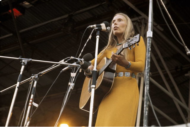 Joni Mitchell playing guitar on stage