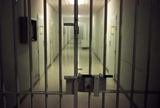 A closed jail cell door looks out into the hallway