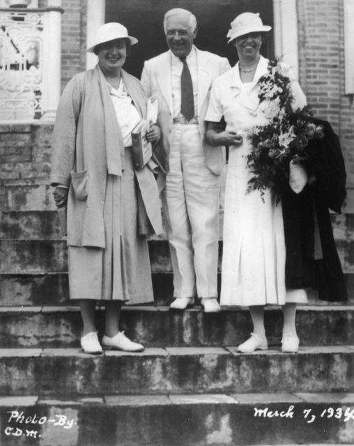 Lorena Hickok and Eleanor Roosevelt pose for a photo with a man between them on some steps