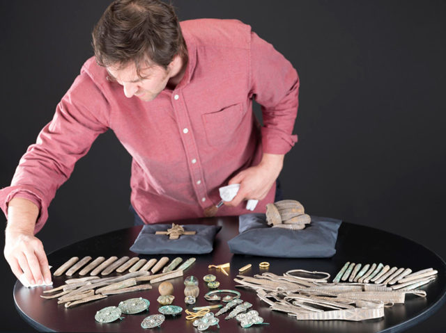 Man stands behind table with multiple artifacts on top