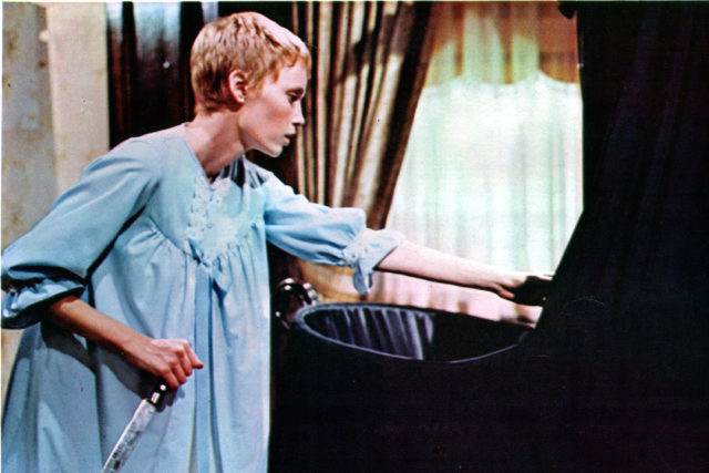 Mia Farrow holding a knife and reaching at a black crib