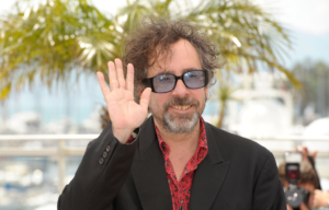 Headshot of Tim Burton wearing sunglasses and waving