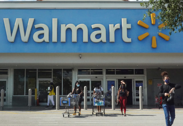 The outside of a Walmart store, people walking with carts in front