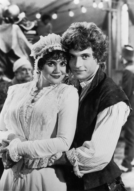 Linda Ronstadt and Rex Smith in costume, a white gown and collared shirt and vest respectively.