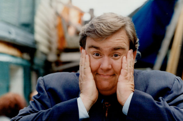 Headshot of John Candy with his hands to his cheeks
