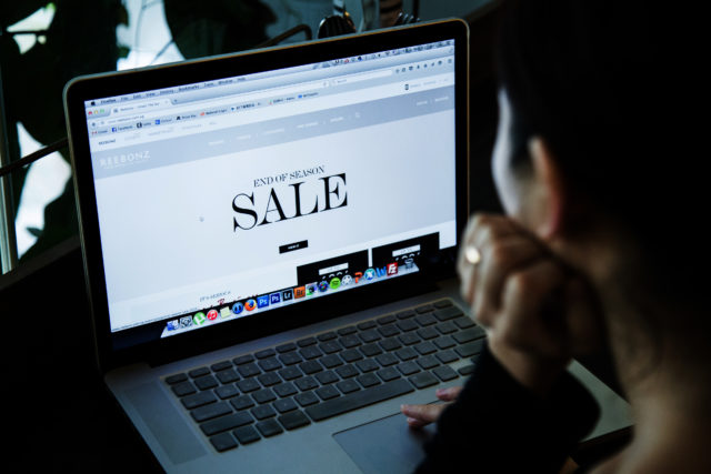 A woman looking at a website on her laptop that reads "SALE"