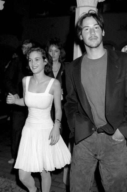 Winona Ryder in a white dress beside Keanu Reeves walking
