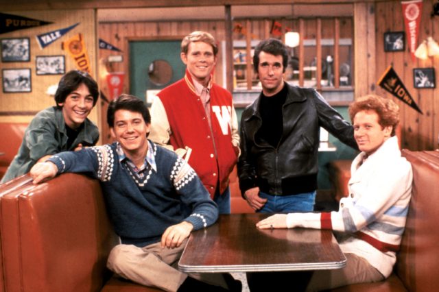 Cast of 'Happy Days' posing in a diner booth as their characters, including Fonzie and Potsie Weber.