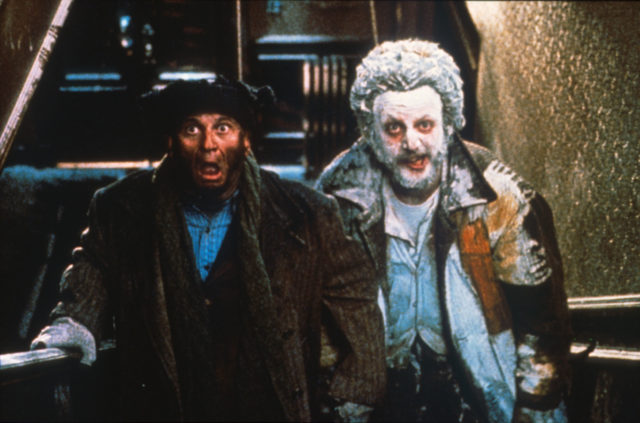 Joe Pesci in winter clothing and a hat, and Daniel Stern covered in a white powder, with startled expressions on their faces.