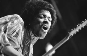 Headshot of Jimi Hendrix singing and playing the guitar