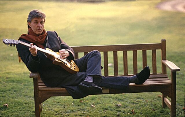 Paul McCartney sitting on a bench