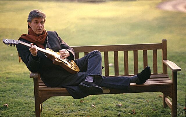 Paul McCartney sitting on a bench 