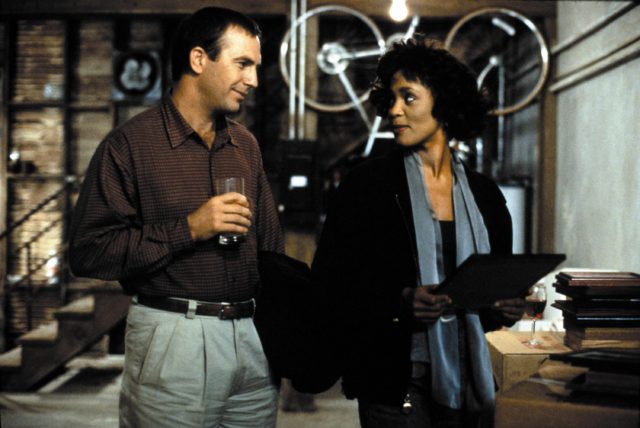 Kevin Costner and Whitney Houston looking at one another in a still from "The Bodyguard."