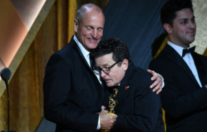 Woody Harrelson hugs Michael J. Fox who holds an Academy Award.