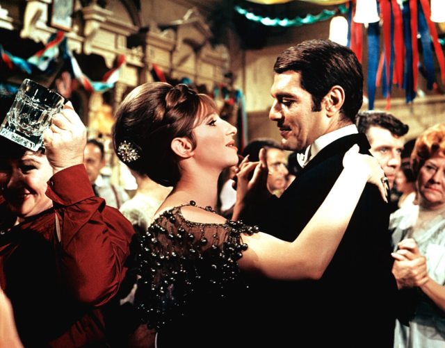 Barbra Streisand and Omar Sherif in elegant clothing dancing together in 'Funny Girl.'