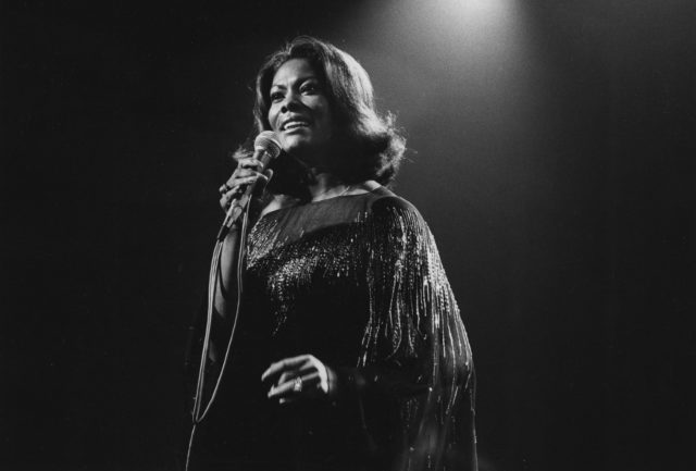 Dionne Warwick in a gown performing at a microphone