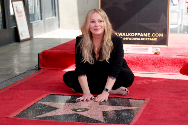 Christina Applegate sitting on the ground with her hands on her Hollywood star