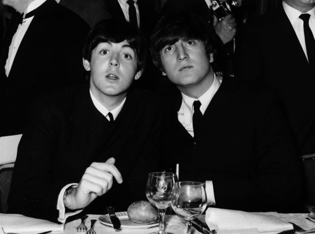 John Lennon and Paul McCartney sitting down and posing together for a photo