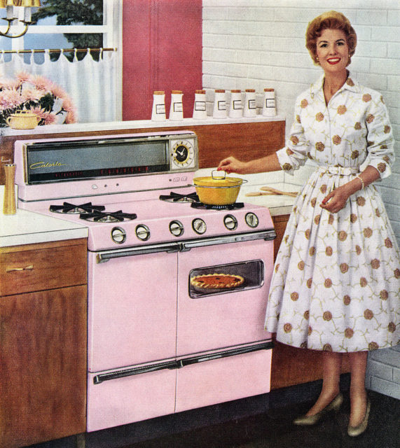 A woman from the 1950s poses at the stove in her kitchen