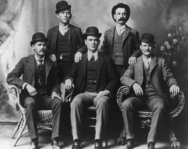 The Wild Bunch pose together for a photograph, they all wear suits.