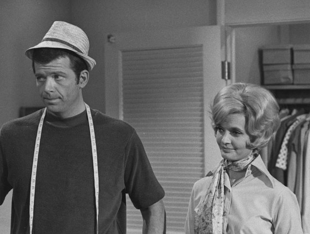 Robert Reed in a t-shirt and fedora beside Florence Henderson in a collared shirt.