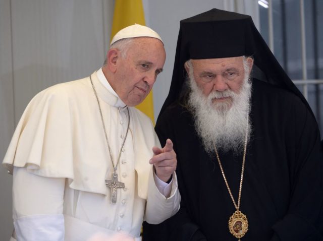 Pope Francis points something out in the distance to Archbishop Ieronymos II stand beside each other.