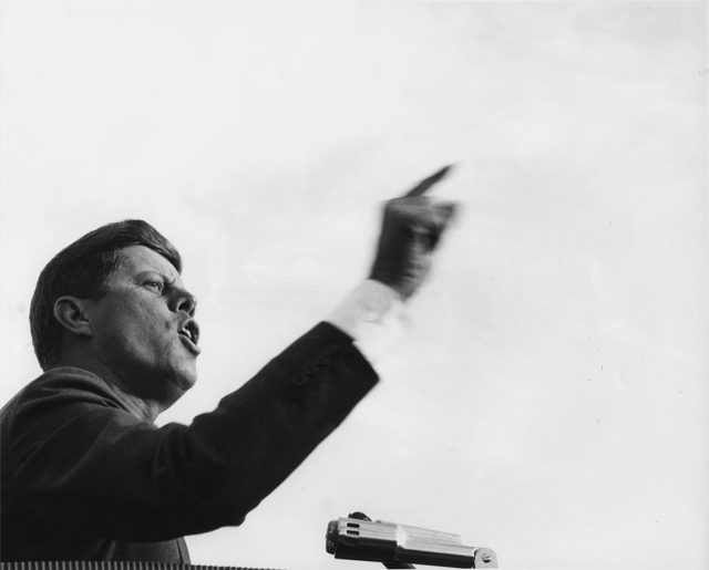 President Kennedy giving a speech while pointing his finger in the air.