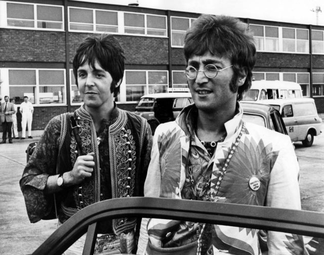 Paul McCartney and John Lennon standing outside of a building, about to get into a car