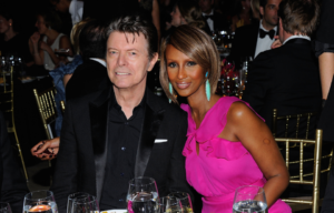 Headshot of Iman and David Bowie smiling for a picture at a dinner table