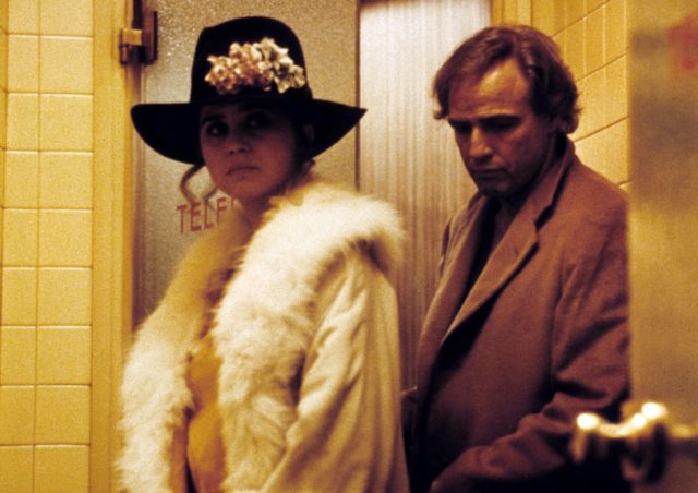 Marlon Brando in a brown jacket and Maria Schneider in a fur coat and large black hat.