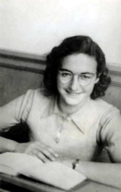 Margot Frank sitting in front of a book smiling at the camera