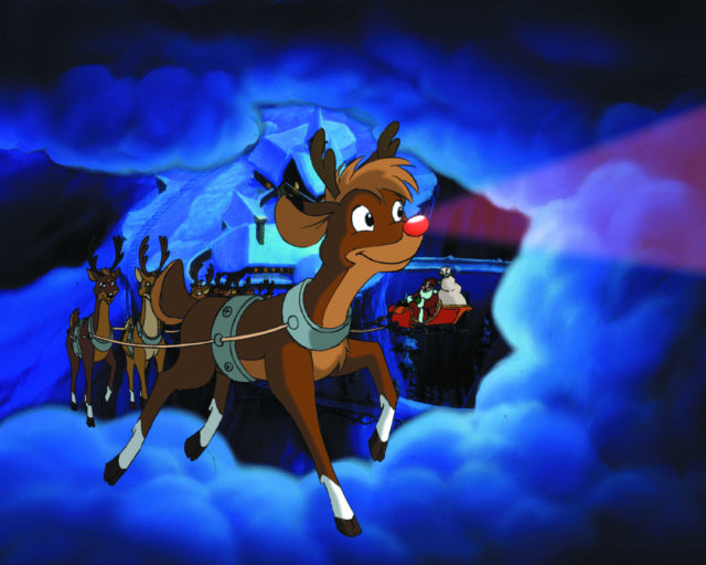 Animated Rudolph the Red-Nosed Reindeer pulling Santa's sleigh in front of other reindeer.