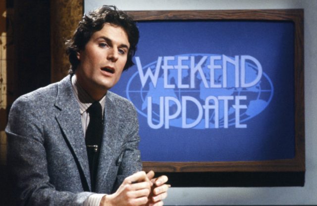 Charles Rocket in front of a sign that reads "Weekend Update"