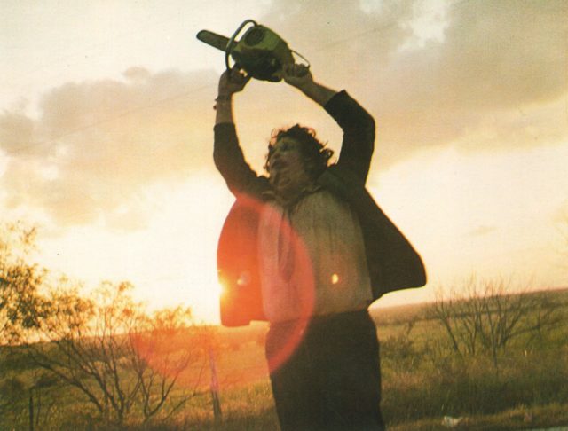 Edwin Neal holding a chainsaw above his head.