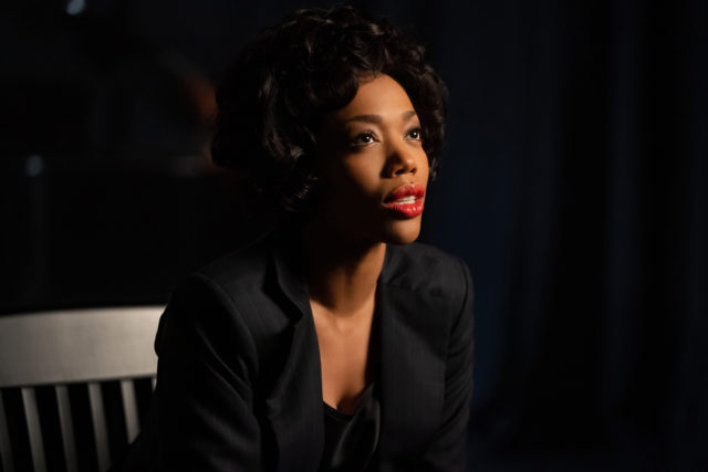 Naomi Ackie as Whitney Houston in a black jacket with bright red lipstick. 
